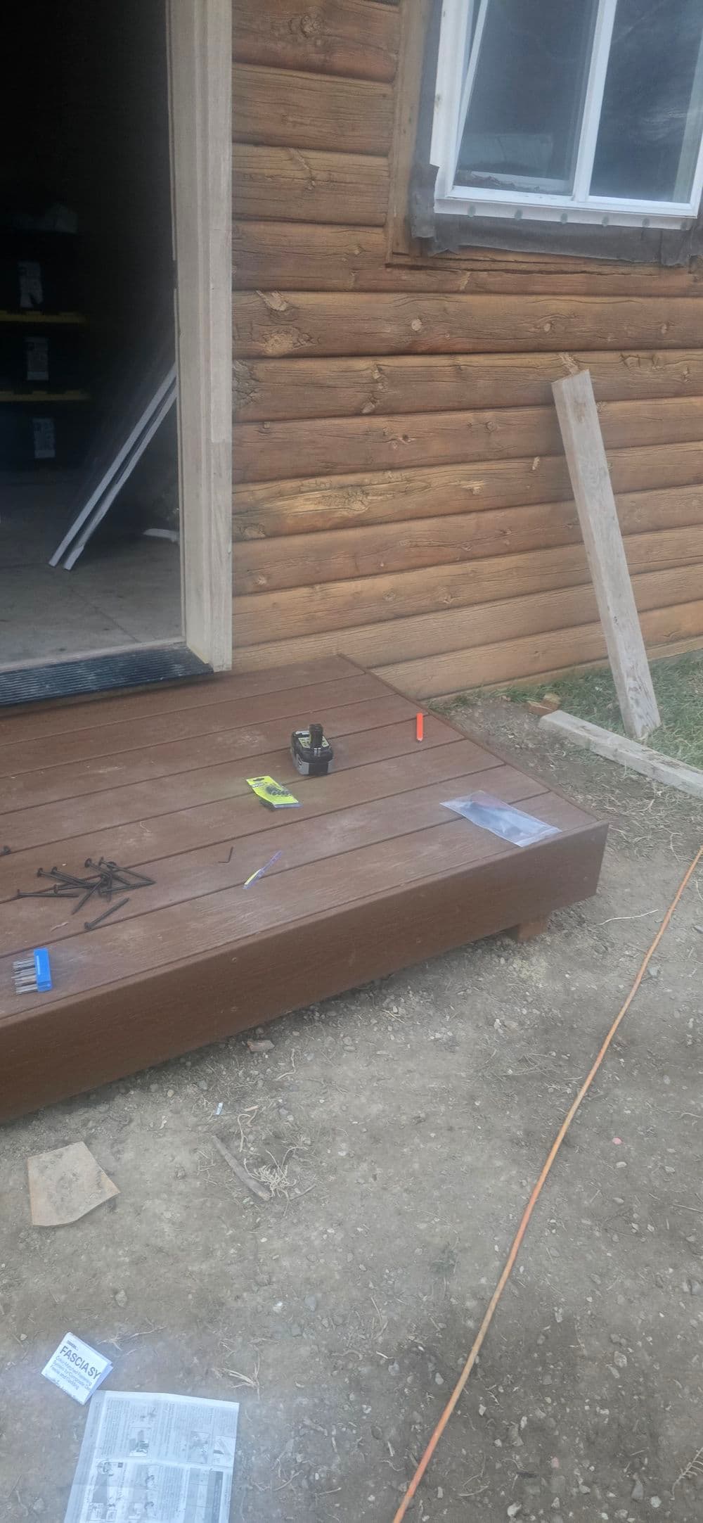 Deck installation in progress with tools and materials on the wooden surface near the entryway.