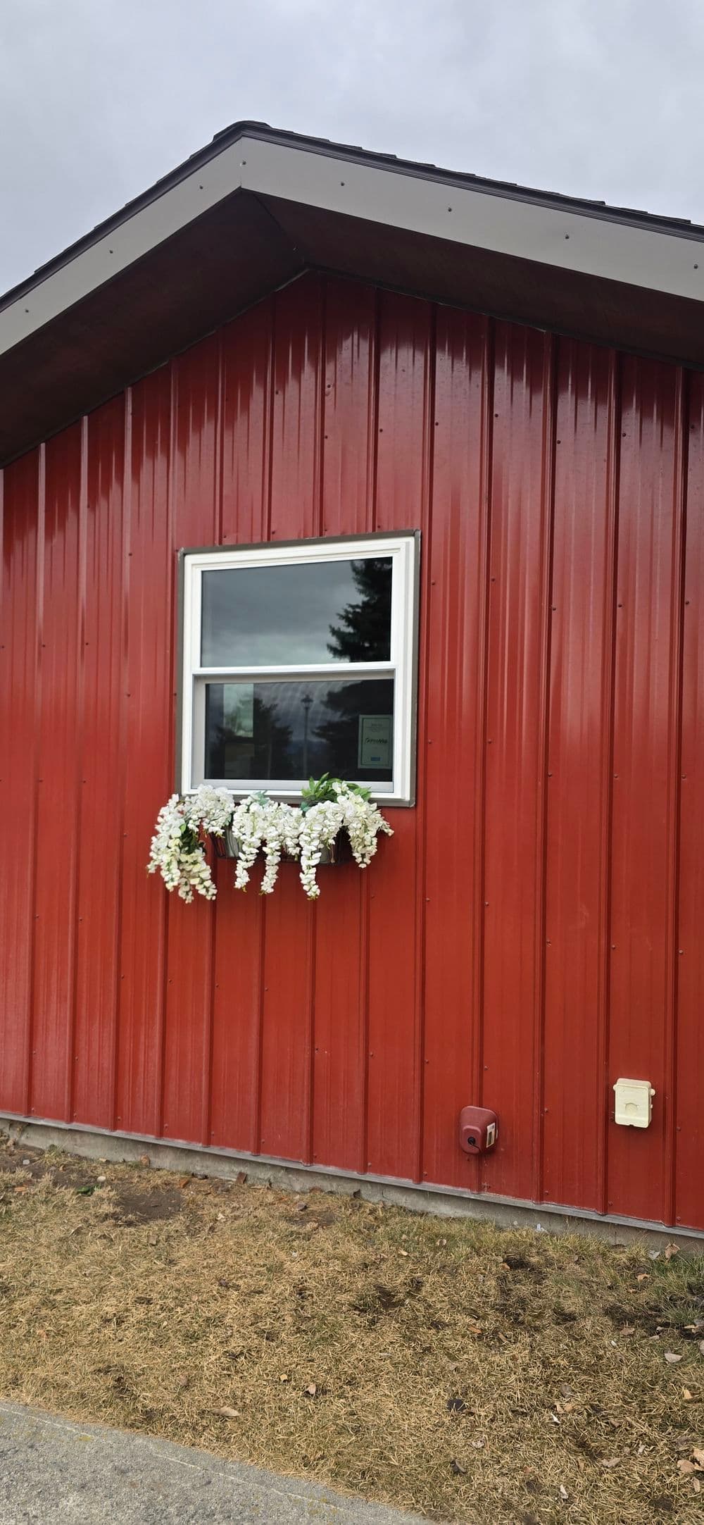 Red barn-style house with a decorative flower box beneath a window.