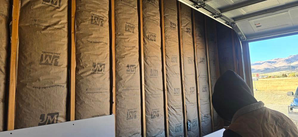Insulation installed in a garage wall with a person observing the process.