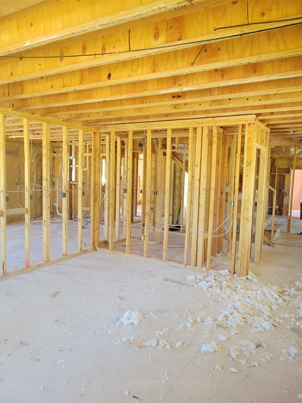 Interior framing of a home under construction, showcasing wooden studs and insulation materials.