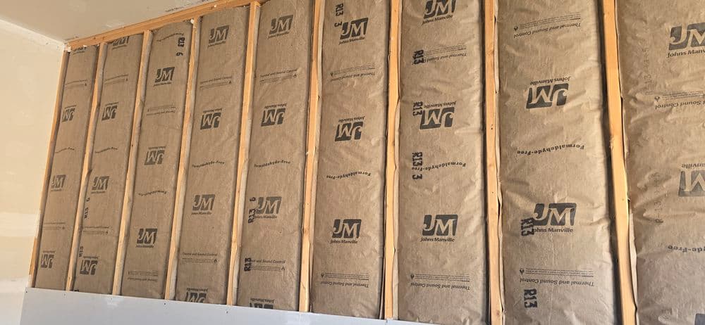 Insulation installation with JM products in walls, showing R13 kraft paper batts.