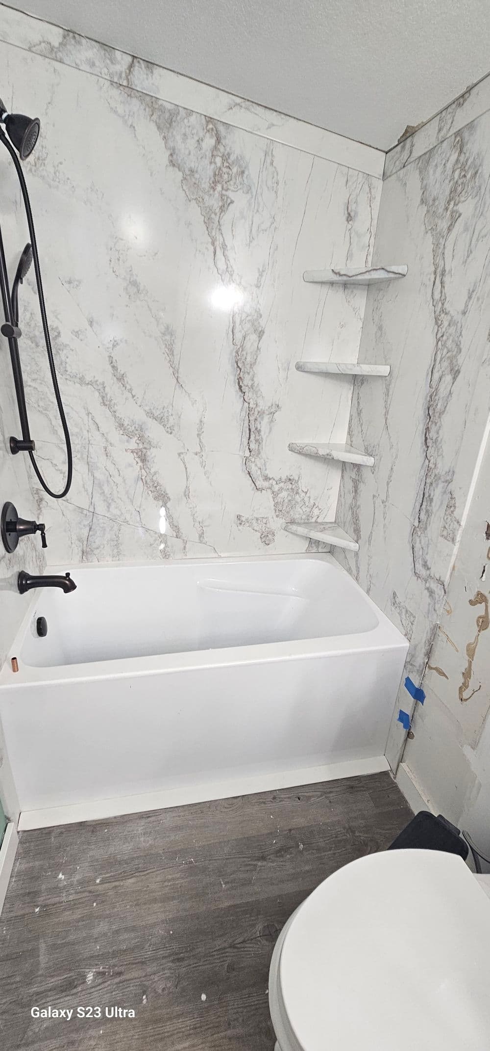 Modern bathroom with a white bathtub, marble walls, and elegant black fixtures.