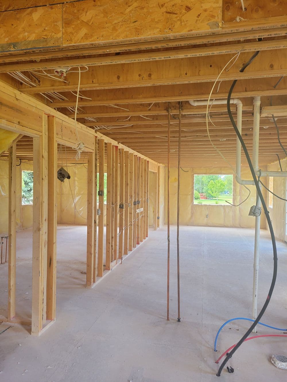 Interior construction of a house showing wooden framing and exposed electrical wiring.