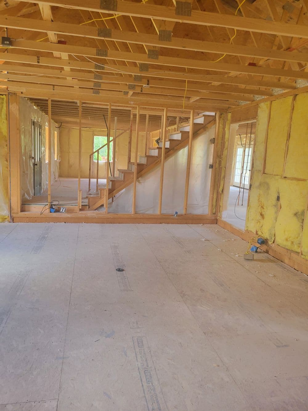 Interior of a partially constructed home showing stairs and exposed framing.