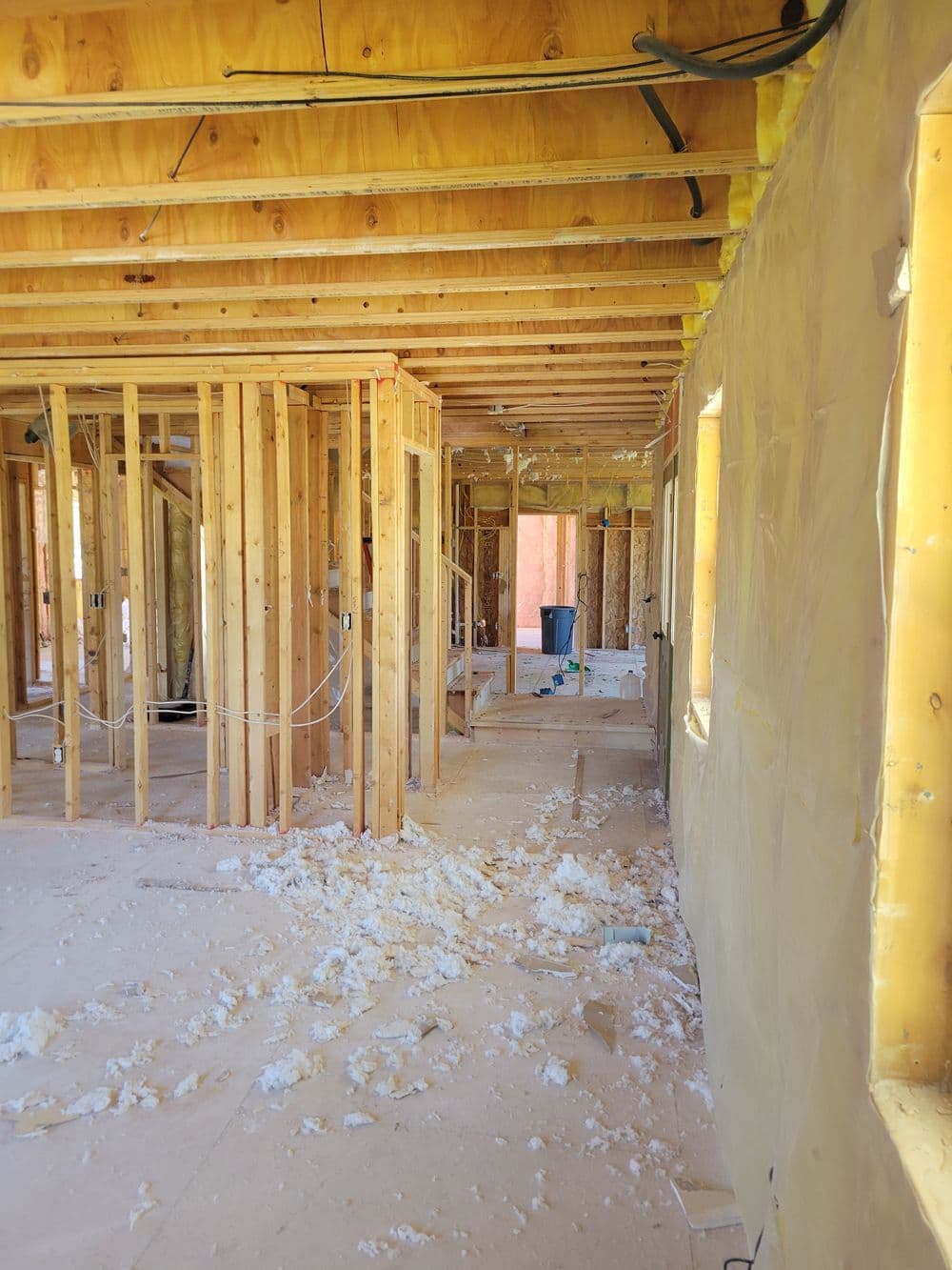 Interior of a residential construction site with exposed framing and insulation materials.