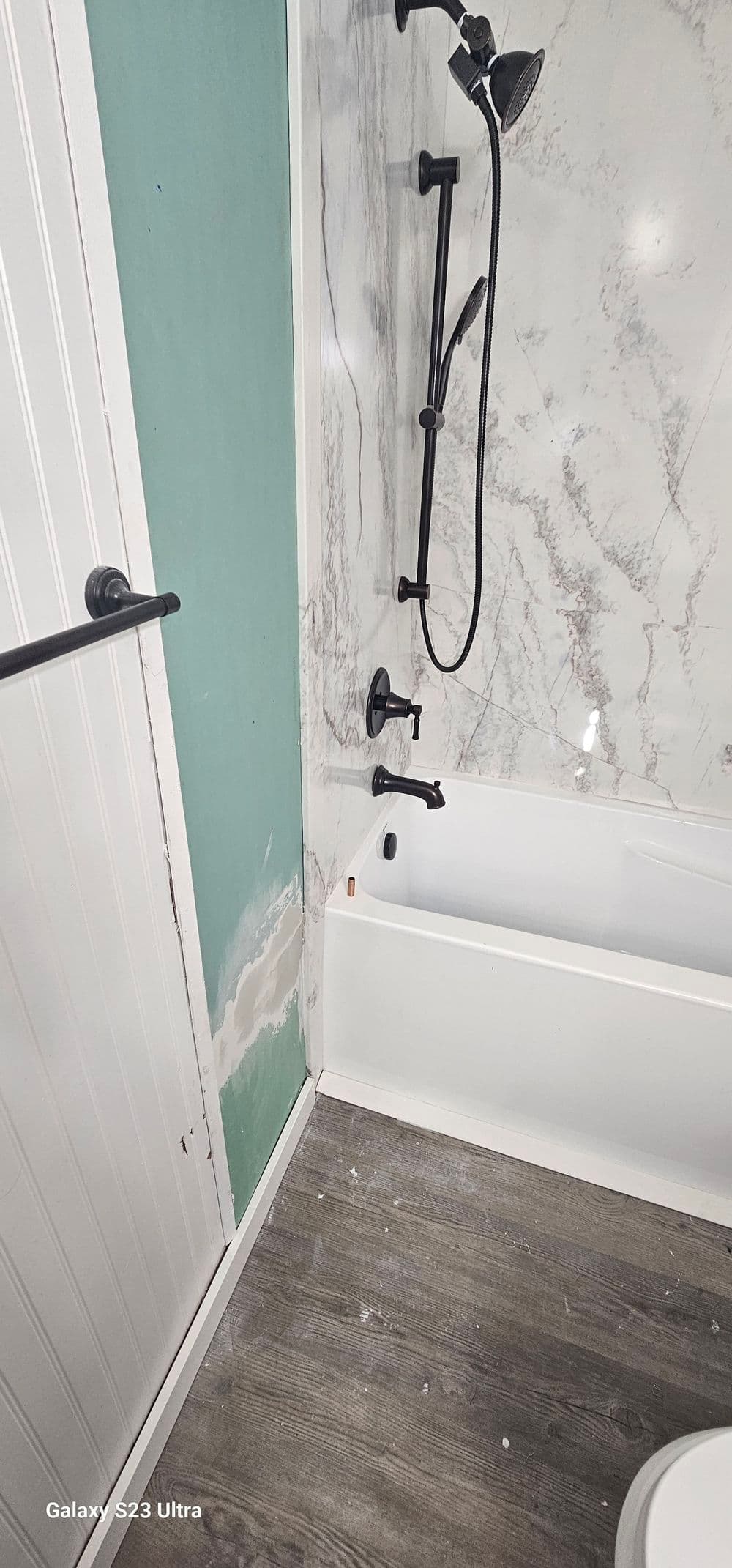 Modern bathroom featuring a marble-tiled shower, tub, and sleek black fixtures.
