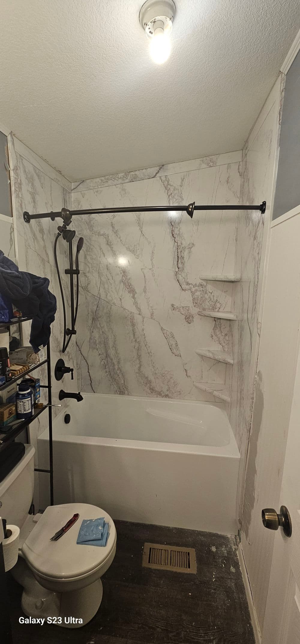 Modern bathroom featuring a white tub, marble walls, shower fixture, and organized storage.