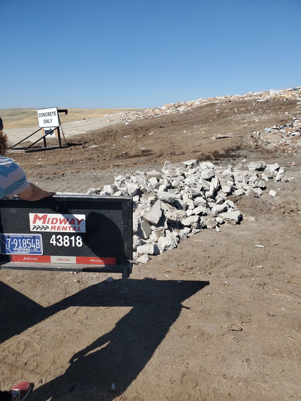 Concrete debris pile at a construction site with a rental truck in the foreground.