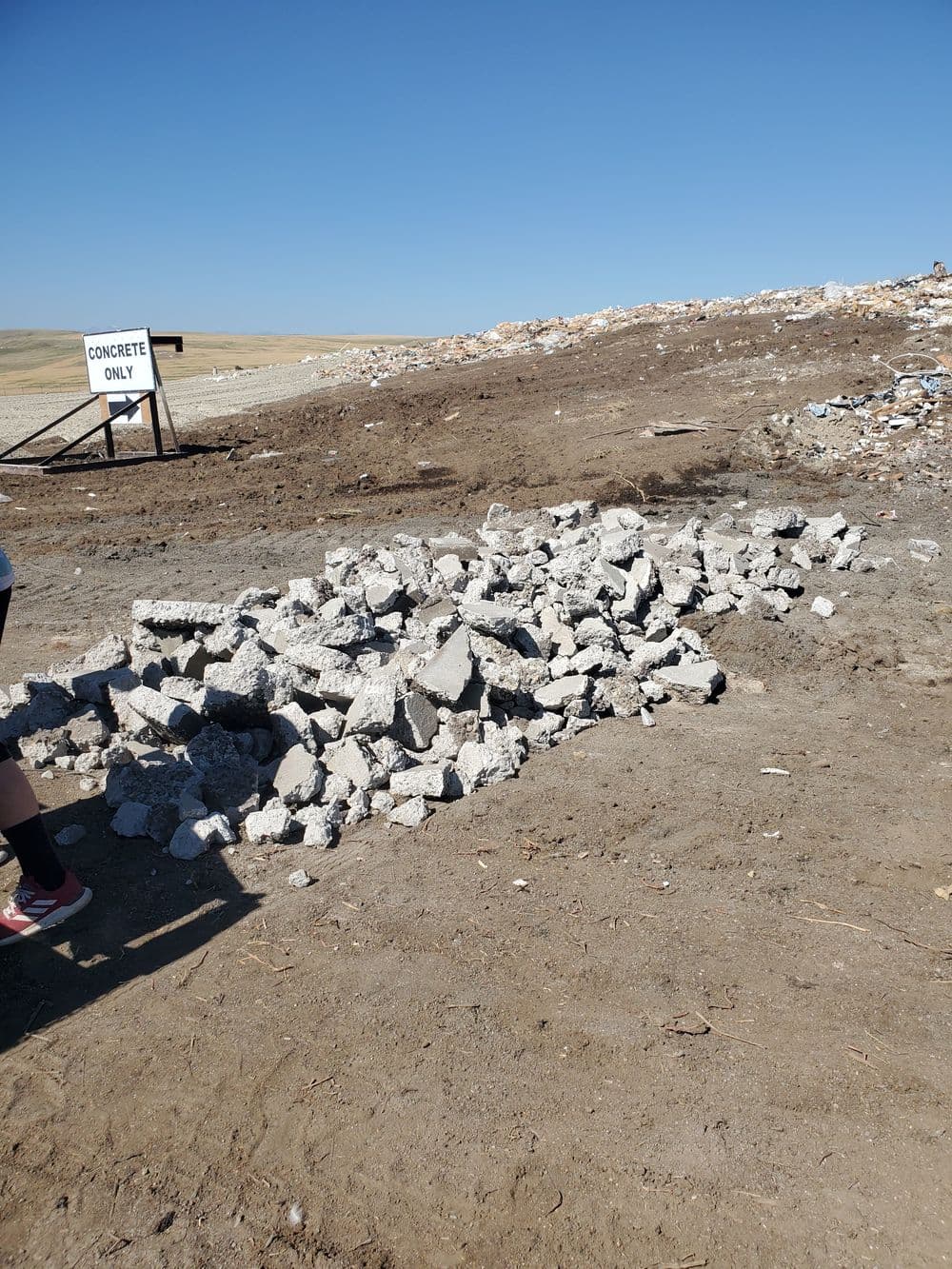 Piles of concrete debris at a construction site under a clear blue sky.
