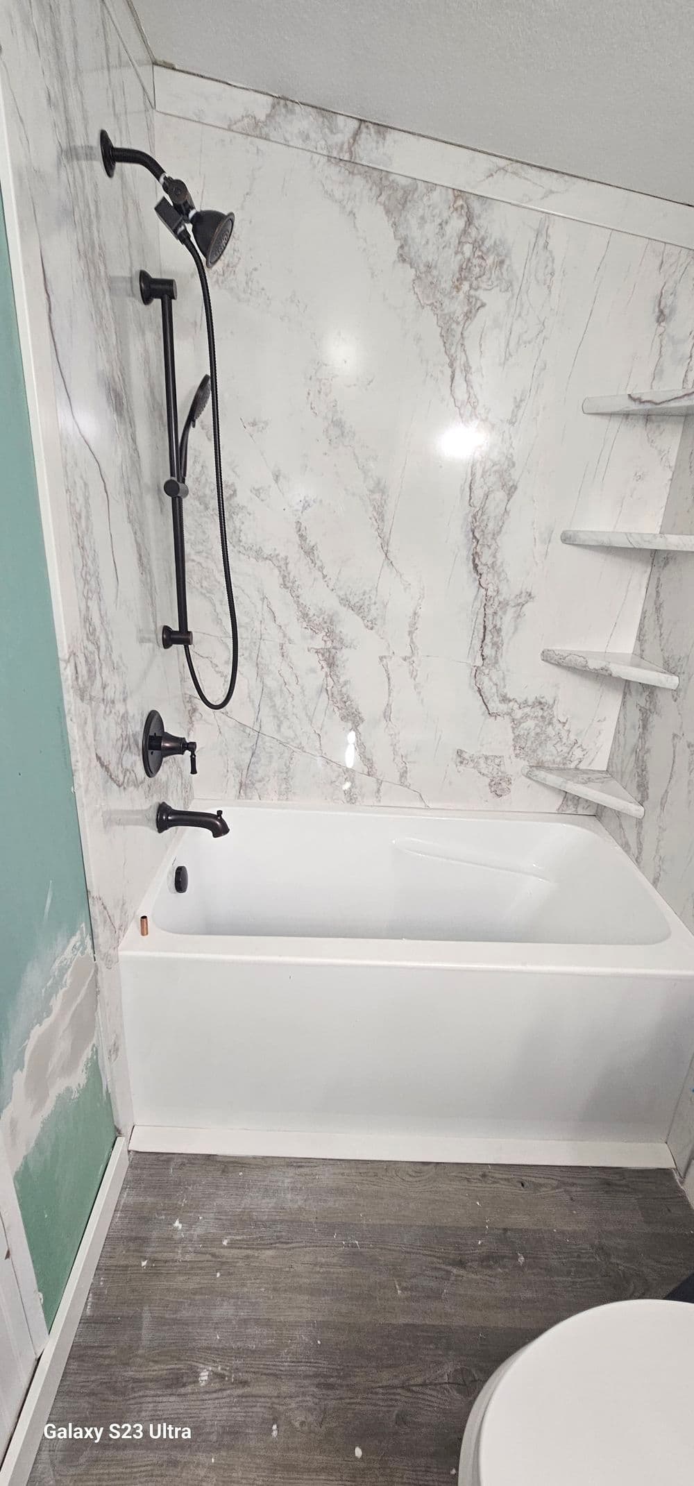 Modern bathtub in a bathroom with marble walls and a sleek shower set.