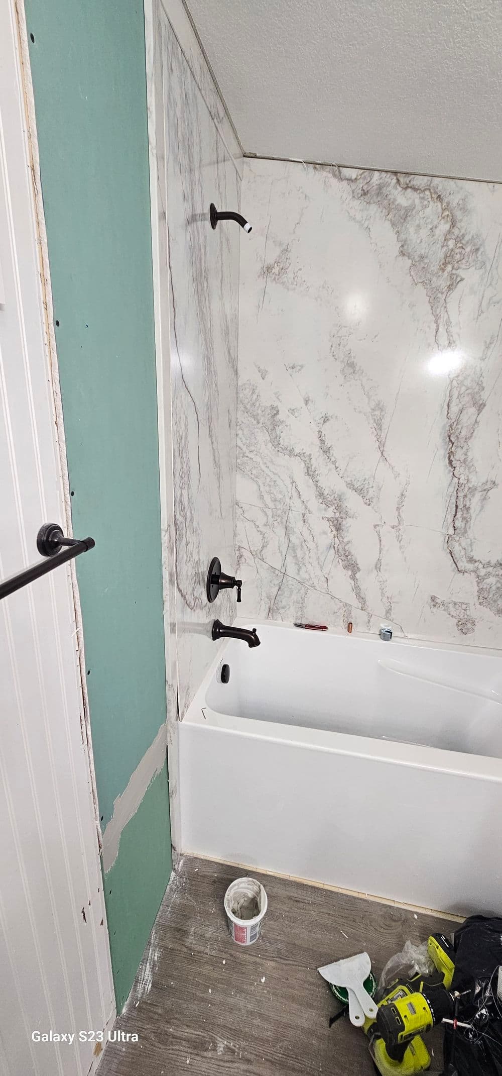Bathroom renovation featuring a bathtub, marble wall, and tools for installation.