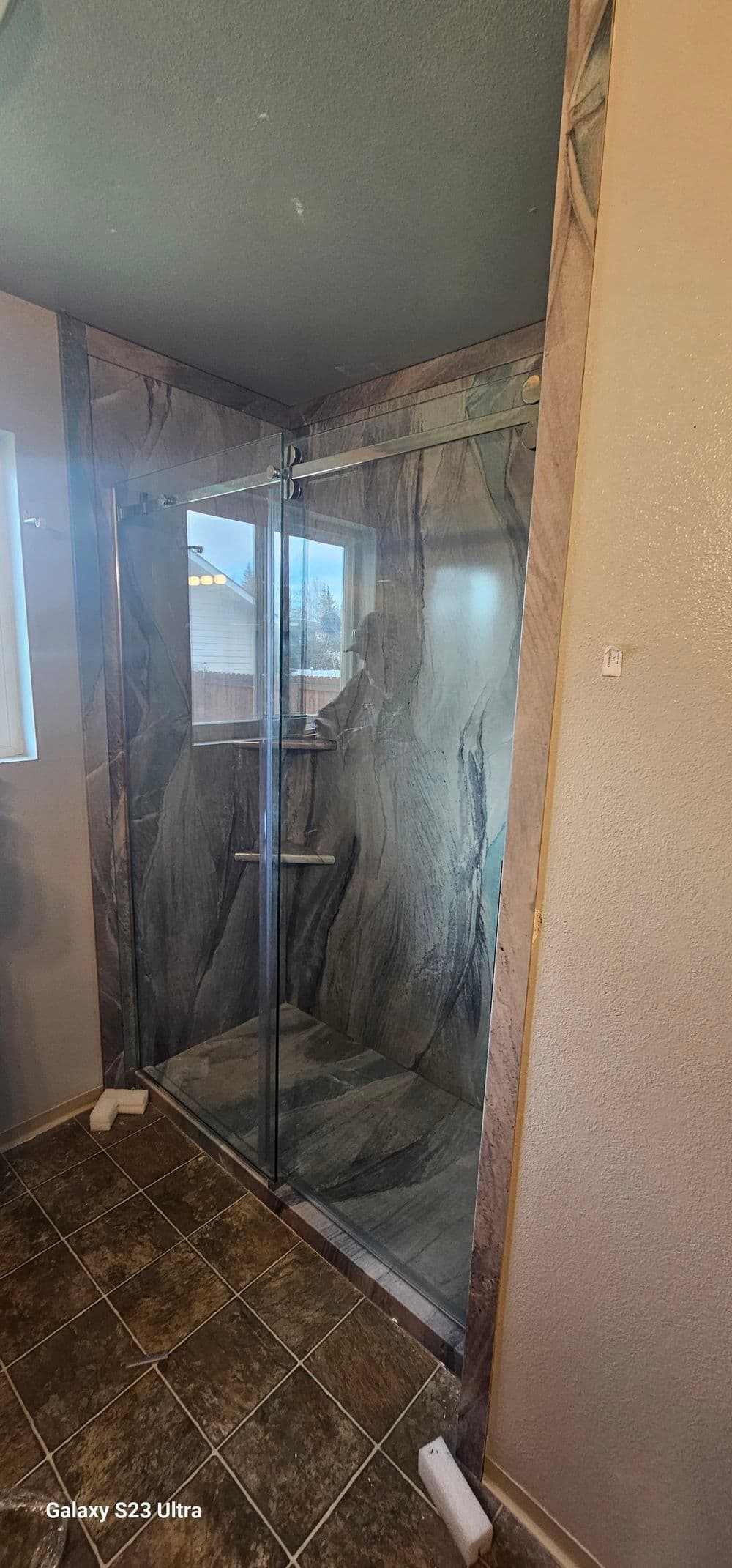 Modern bathroom featuring a stylish glass shower with marble walls and tiled floor.