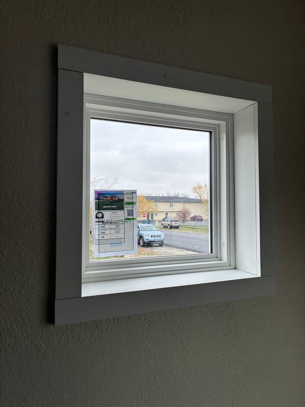 Interior window with a view of a parking lot and a document taped to the glass.