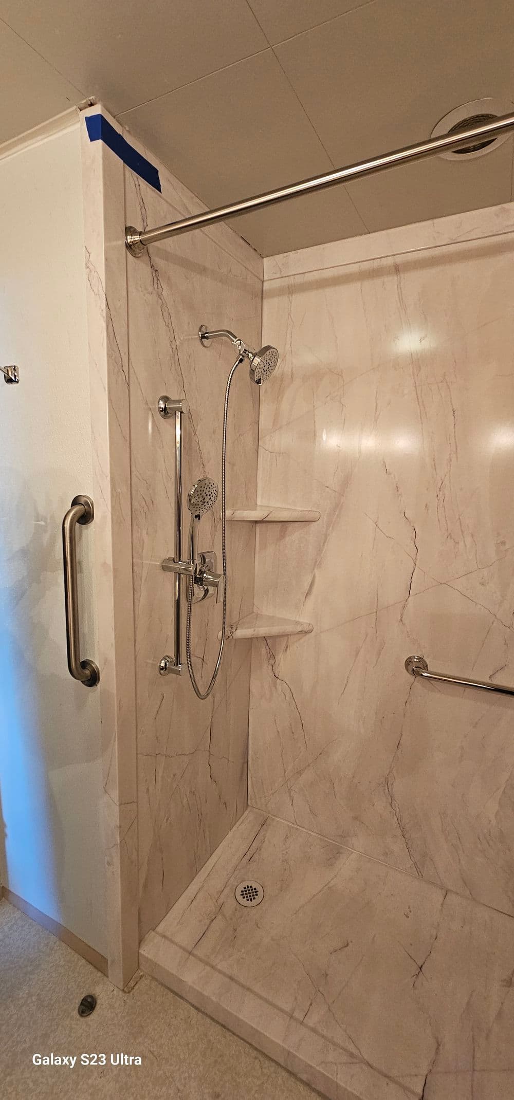 Modern shower with marble walls, dual shower heads, and grab bar for accessibility.