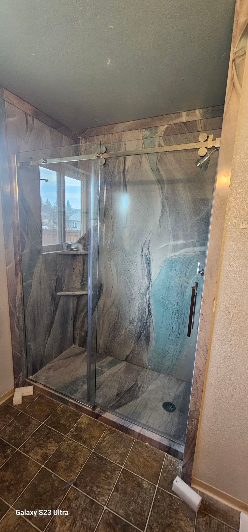 Modern glass shower enclosure with elegant marble walls and tiled floor in a bathroom setting.
