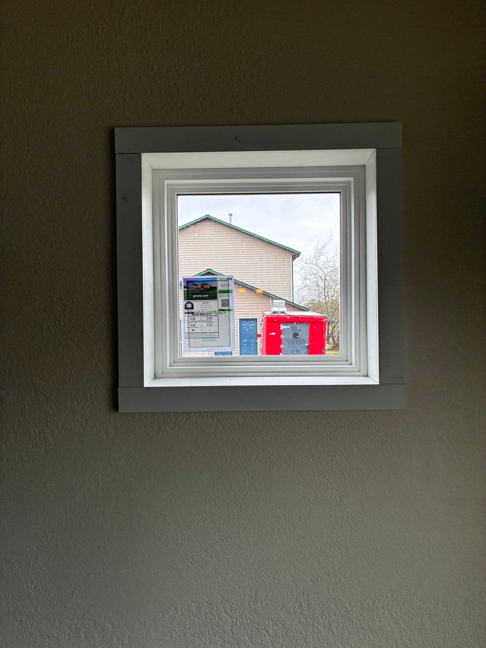 View from an interior window showing a house exterior and a red construction trailer.